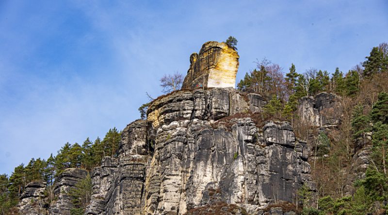 Chiseled Yellow Sandstone abutment standing high above grey sandstone cliffs.