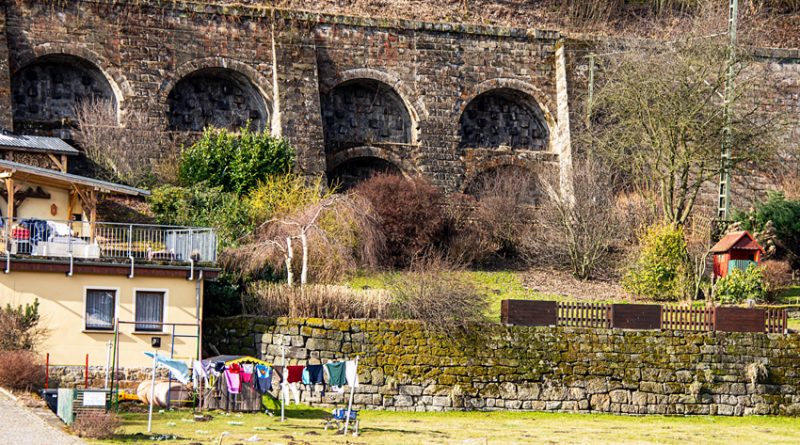 Laundry hanging in a yard in the foreground with an arched Stone Viaduct in the background