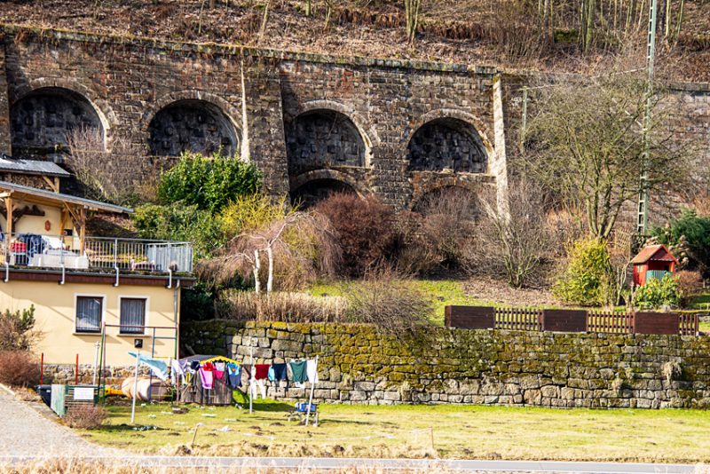 Laundry hanging in a yard in the foreground with an arched Stone Viaduct in the background