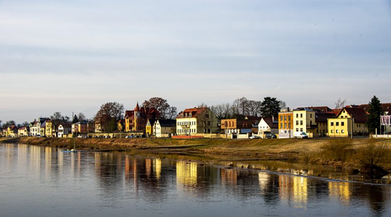 Colorful houses lining the banks of the Elbe River downstream from Dresden and reflected in a placid river.