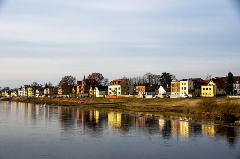 Colorful houses lining the banks of the Elbe River downstream from Dresden and reflected in a placid river.