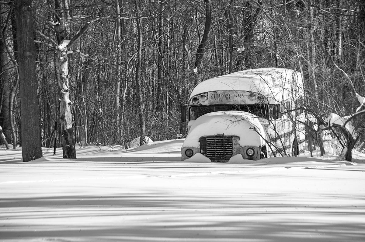 Snow covering a deteriorated and abandoned school bus